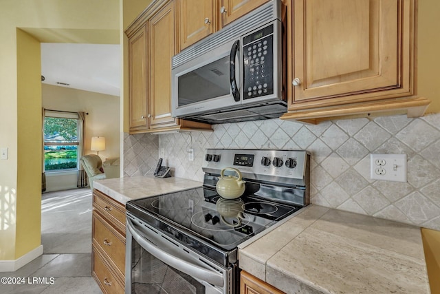 kitchen featuring tasteful backsplash, light tile patterned floors, and stainless steel appliances