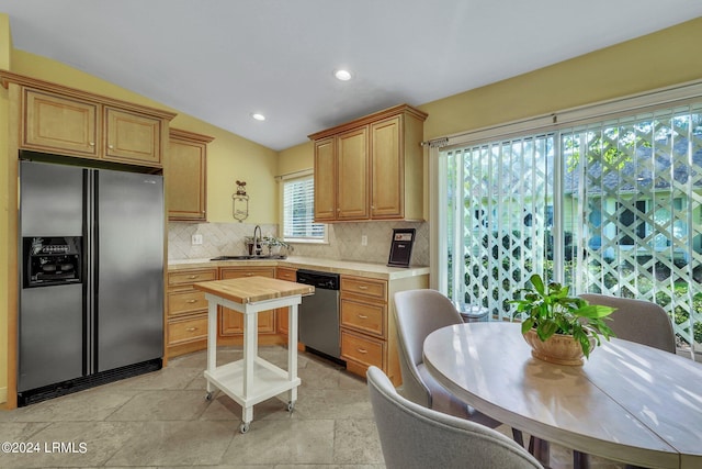 kitchen with stainless steel appliances, lofted ceiling, sink, and backsplash