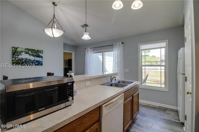 55 Broadland Cir, Bluffton, SC 29910 - kitchen with white appliances, brown cabinets, lofted ceiling, wood finished floors, and light countertops
