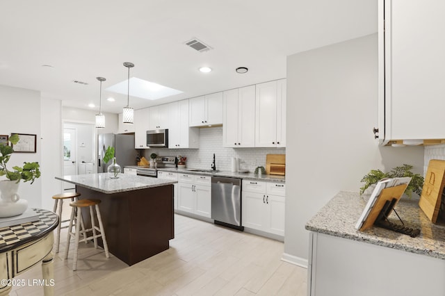 485 Bb Sams Dr, Saint Helena Island, SC 29920 - kitchen featuring stainless steel appliances, backsplash, a breakfast bar, white cabinetry, and a kitchen island