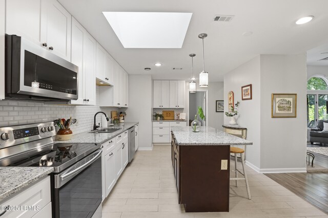 485 Bb Sams Dr, Saint Helena Island, SC 29920 - kitchen featuring stainless steel appliances, decorative backsplash, a kitchen island, white cabinets, and a kitchen breakfast bar