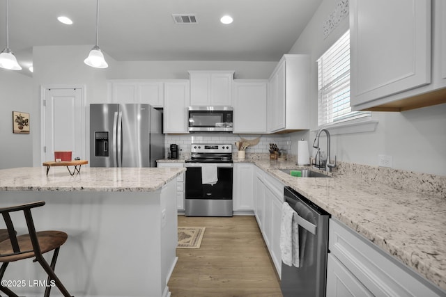 kitchen with white cabinetry, sink, pendant lighting, and stainless steel appliances