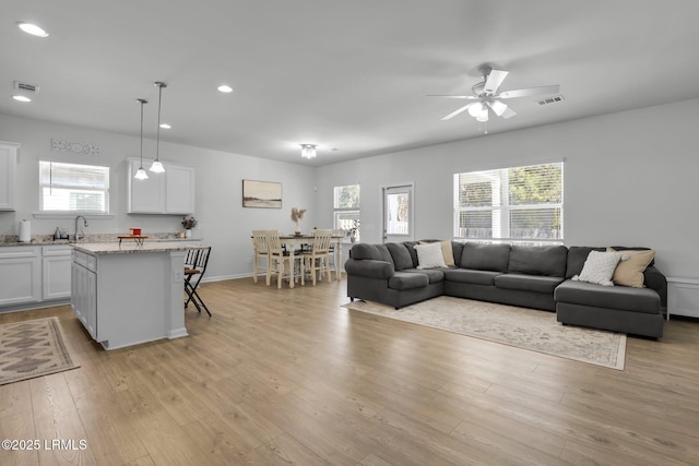 living room featuring sink, light hardwood / wood-style flooring, and ceiling fan