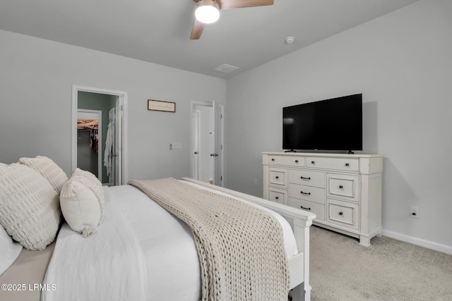 carpeted bedroom with ceiling fan, a walk in closet, and a closet