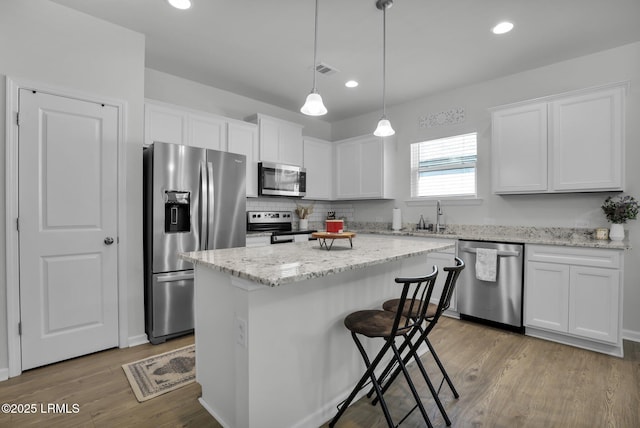 kitchen with pendant lighting, sink, appliances with stainless steel finishes, a center island, and white cabinets