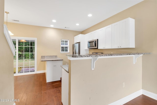 kitchen featuring appliances with stainless steel finishes, a kitchen bar, kitchen peninsula, and white cabinets