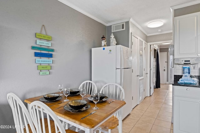 tiled dining space featuring ornamental molding and a textured ceiling