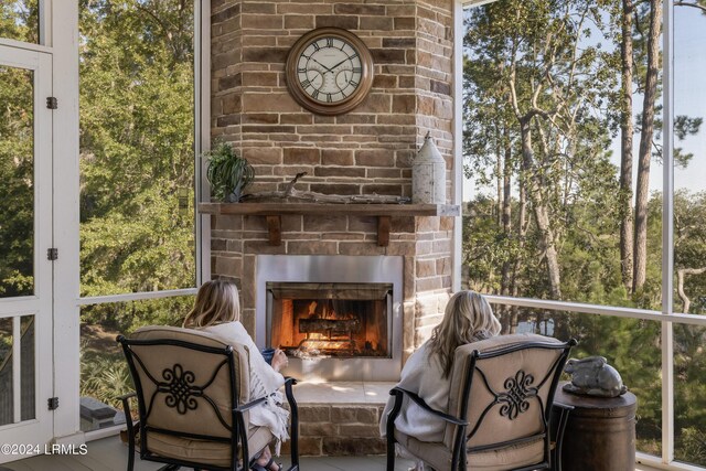 sunroom featuring an outdoor stone fireplace