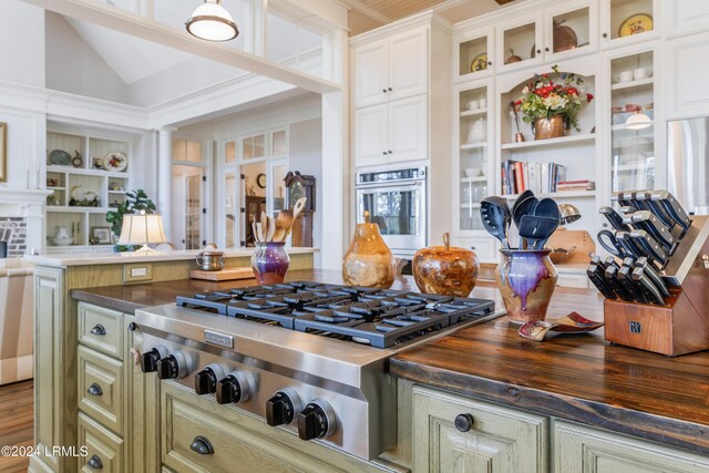 kitchen featuring stainless steel appliances, vaulted ceiling, white cabinets, and ornate columns