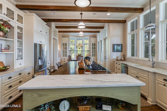 kitchen with sink, decorative light fixtures, light stone countertops, and appliances with stainless steel finishes