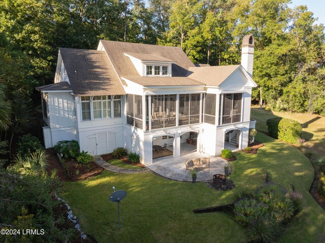 rear view of house featuring a patio area, a sunroom, and a lawn