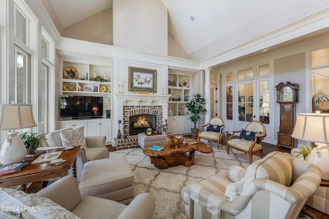 living room with built in features, high vaulted ceiling, a fireplace, french doors, and ornate columns