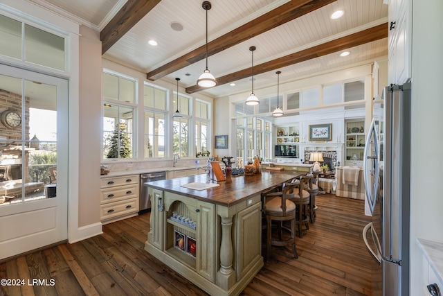 kitchen with wooden counters, a kitchen breakfast bar, a kitchen island, stainless steel appliances, and beam ceiling