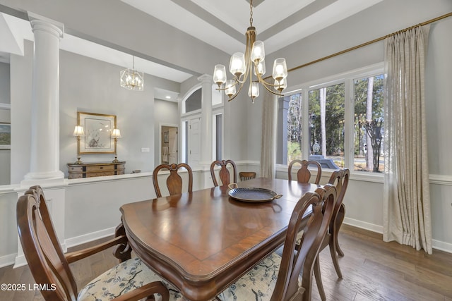 dining area with a notable chandelier, wood-type flooring, and ornate columns