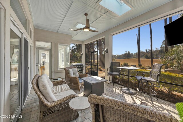 sunroom / solarium featuring a skylight and ceiling fan