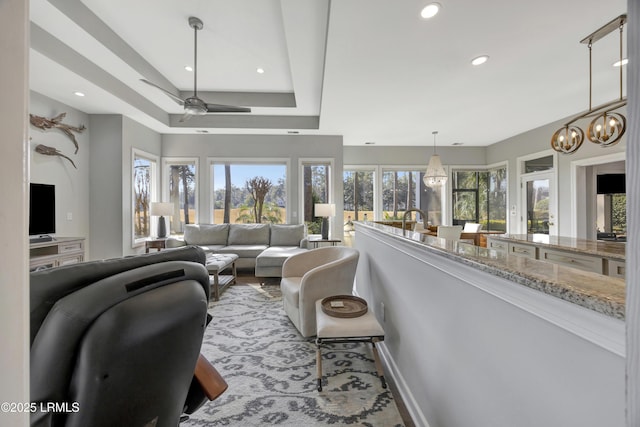 living room with a raised ceiling and ceiling fan