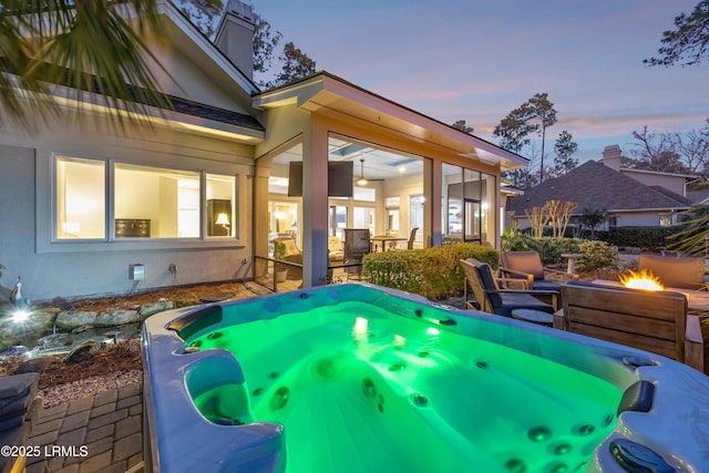 patio terrace at dusk featuring an outdoor hot tub and an outdoor fire pit