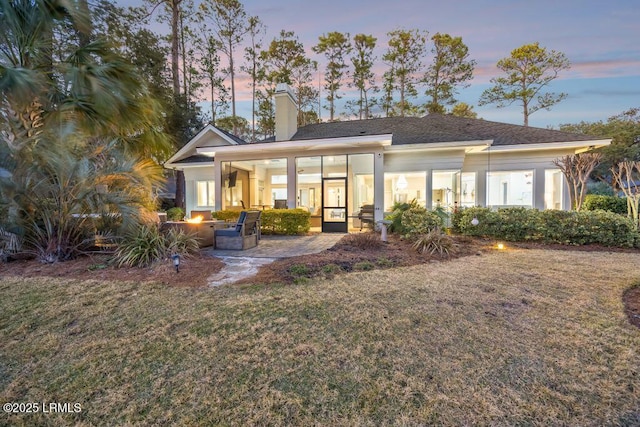 back house at dusk with a patio, a yard, and an outdoor fire pit