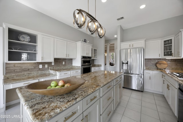 kitchen with light stone counters, stainless steel appliances, a center island, and white cabinets