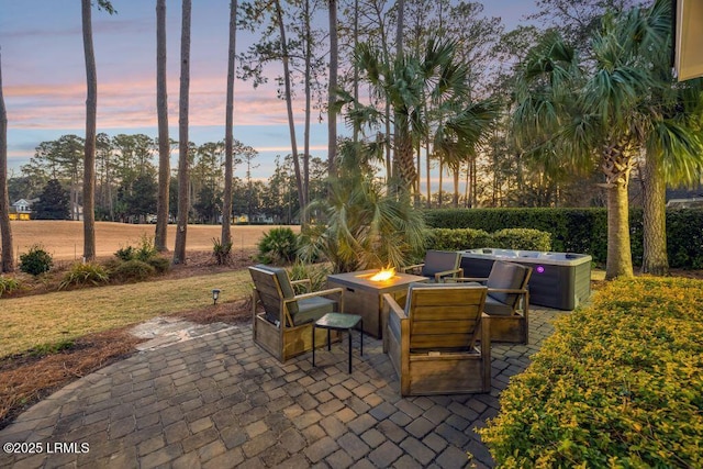 patio terrace at dusk with a hot tub and an outdoor fire pit