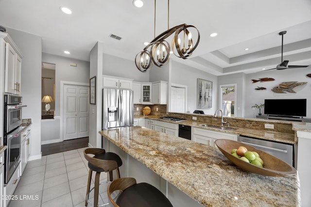 kitchen with stainless steel appliances, white cabinetry, hanging light fixtures, and kitchen peninsula