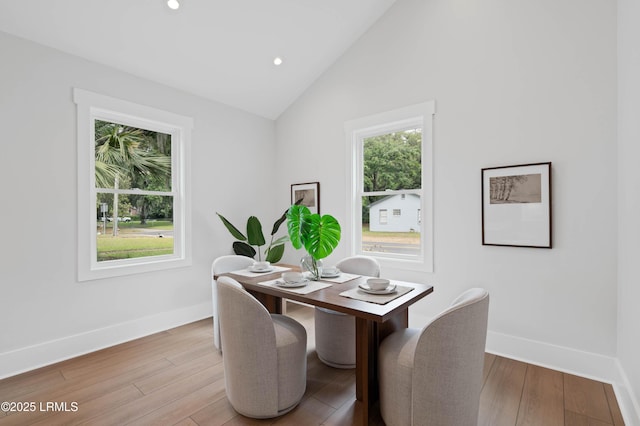 dining space with baseboards, lofted ceiling, and light wood-type flooring
