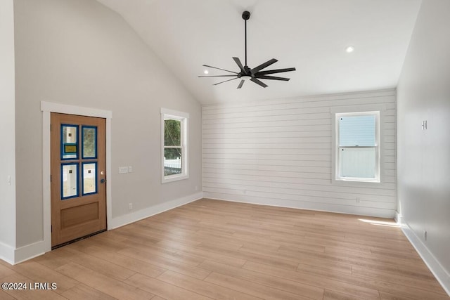 interior space featuring ceiling fan, lofted ceiling, wooden walls, and light hardwood / wood-style floors