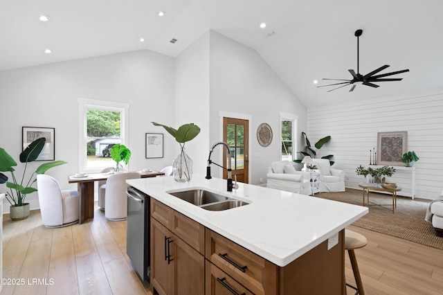kitchen featuring light wood-style flooring, open floor plan, a sink, and high vaulted ceiling