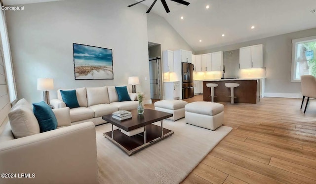 living room with ceiling fan, high vaulted ceiling, sink, and light hardwood / wood-style flooring