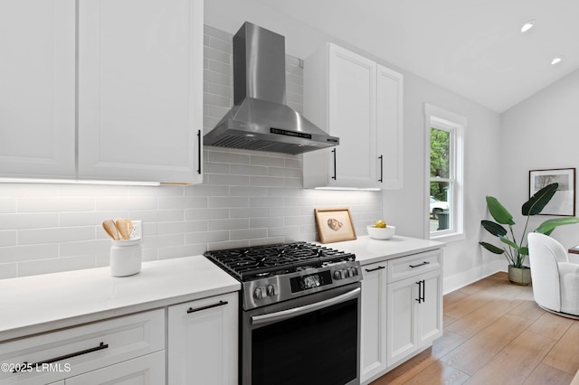 kitchen featuring decorative backsplash, light wood finished floors, wall chimney range hood, and stainless steel gas range