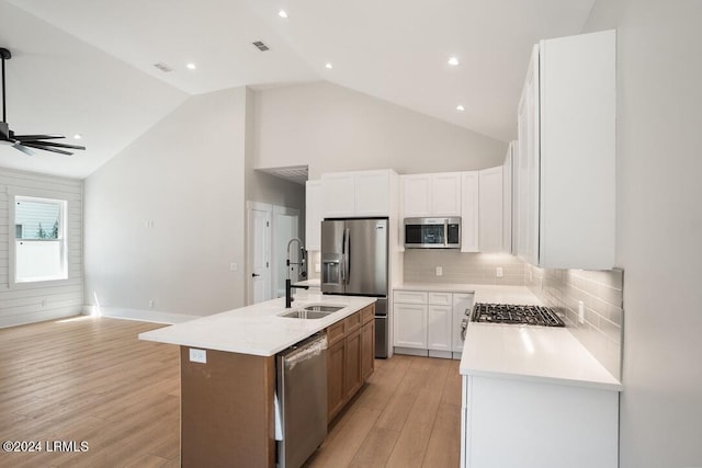 kitchen with sink, appliances with stainless steel finishes, tasteful backsplash, an island with sink, and white cabinets