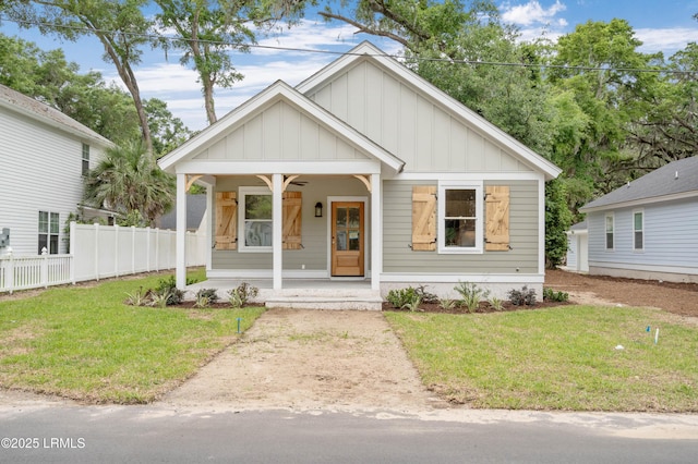 view of front facade with board and batten siding, fence, covered porch, and a front yard