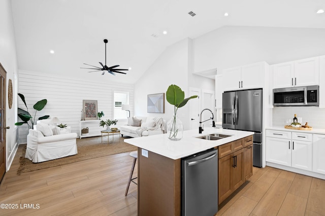 kitchen with a sink, light countertops, high vaulted ceiling, stainless steel appliances, and open floor plan