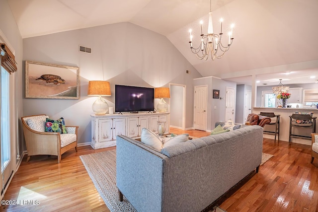 living room with high vaulted ceiling, a notable chandelier, and light wood-type flooring