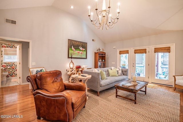 living room featuring high vaulted ceiling, light hardwood / wood-style floors, and a chandelier