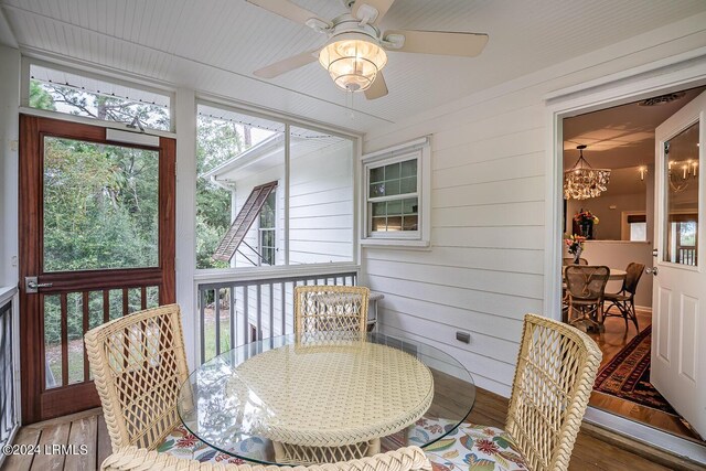 sunroom / solarium with ceiling fan with notable chandelier and a wealth of natural light