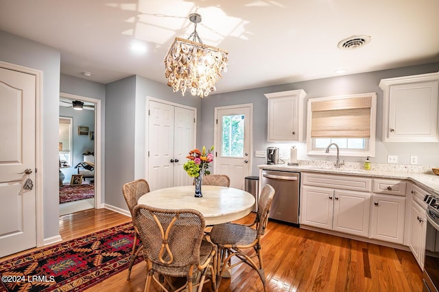 dining space with sink, a notable chandelier, and light wood-type flooring