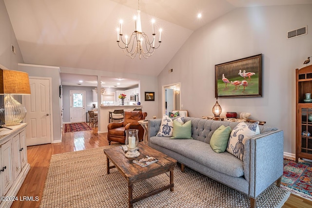 living room with high vaulted ceiling, light hardwood / wood-style flooring, and a notable chandelier