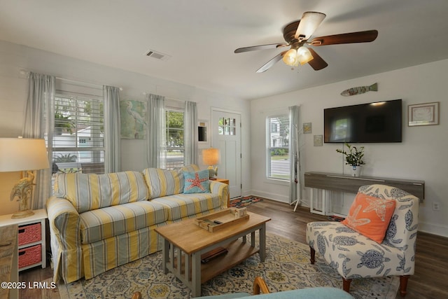 living room with baseboards, visible vents, wood finished floors, and a ceiling fan