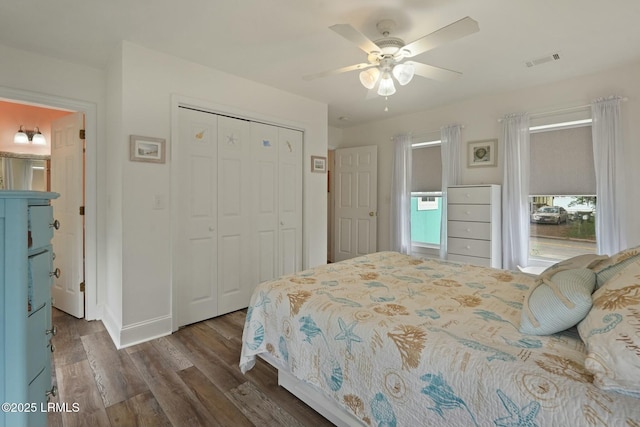 bedroom with visible vents, ceiling fan, baseboards, a closet, and wood finished floors