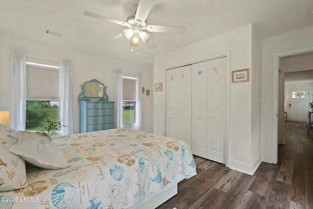 bedroom with visible vents, dark wood-style floors, a closet, baseboards, and a ceiling fan