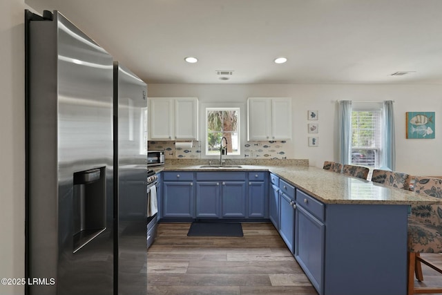 kitchen featuring stainless steel appliances, blue cabinetry, a peninsula, and a sink