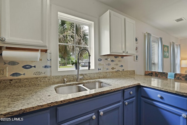 kitchen featuring blue cabinets, a healthy amount of sunlight, and a sink