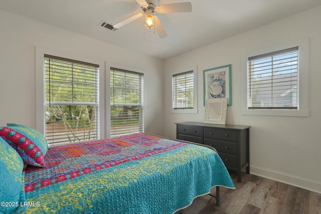 bedroom featuring wood finished floors, visible vents, baseboards, and multiple windows