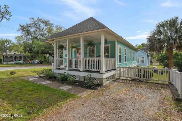 view of front of property with a front lawn, a shingled roof, covered porch, driveway, and fence
