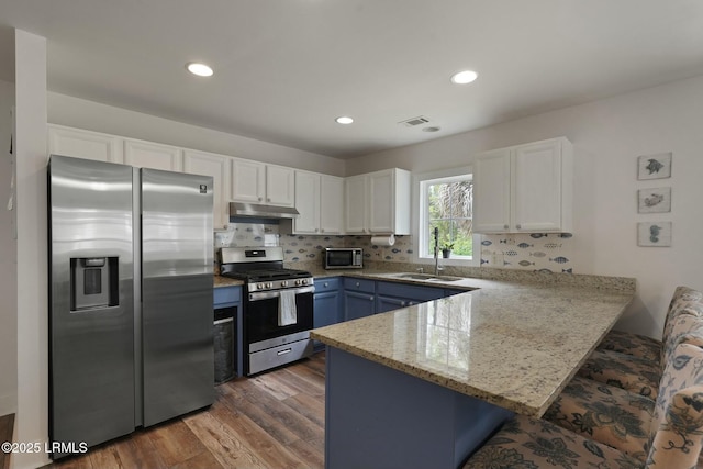 kitchen with a sink, visible vents, stainless steel appliances, under cabinet range hood, and a peninsula