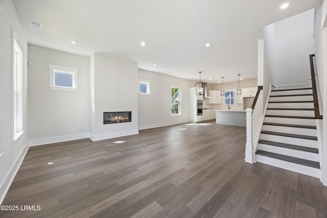 14 Skipperling Ct, Bluffton, SC 29909 - unfurnished living room with recessed lighting, a glass covered fireplace, dark wood-style flooring, baseboards, and stairway