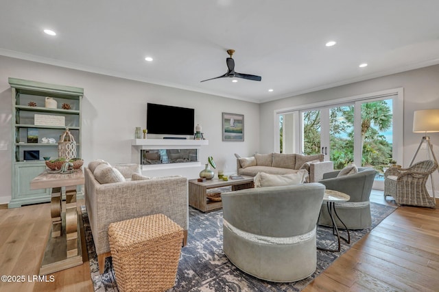 living room featuring ceiling fan, ornamental molding, and light hardwood / wood-style flooring