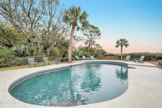 pool at dusk featuring a patio area