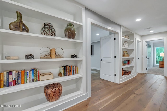 corridor featuring built in shelves and wood-type flooring